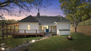 A two-story house with a covered porch, a front door, and a small shed.