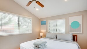 A bedroom with a bed, two windows with blinds, a ceiling fan, and wall art. - Hot Tub & Patio: Modern Sedona Home! (Sedona)