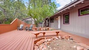 A wooden deck with outdoor seating, a small garden area, and a building with a door and windows. - Hot Tub & Patio: Modern Sedona Home! (Sedona)