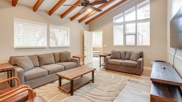 A spacious living room with a high ceiling, wooden beams, two sofas, a coffee table, and a TV. - Hot Tub & Patio: Modern Sedona Home! (Sedona)