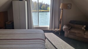 Une chambre avec une grande fenêtre, un lit, une armoire, un canapé et une lampe.
