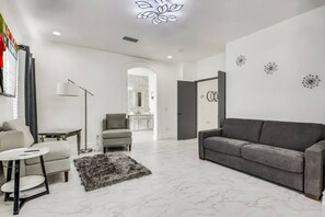Una sala de estar moderna con un sofá gris, una mesita redonda y una lámpara de pie.