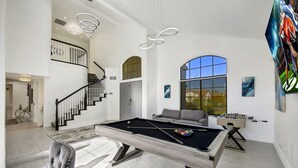A spacious living area with a pool table, a sofa, and a foosball table. - Desert Pearl: Pool, Spa, Pool Table, Foosball, EV! (Indio)
