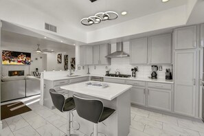 A modern kitchen with a central island, bar stools, and a built-in oven.