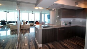A modern kitchen with a central island, dark cabinetry, and a large window providing natural light. - Castle BTH2 Beach Townhouse, Pool and Direct Beach Access from the unit! Gym, Tennis, Free Valet (Miami Beach)