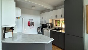 A modern kitchen with white cabinets, a grey refrigerator, a microwave, and a coffee maker.