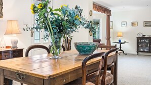 Une salle à manger avec une table en bois, des chaises, un vase de fleurs et un bol décoratif.
