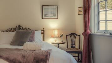 A neatly made bed with a brown throw blanket, a bedside lamp, and a framed picture on the wall.