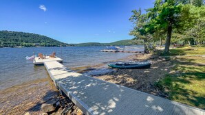 A lakeside dock with boats, a wooden pier, and a grassy area with trees. - Iconic Private DCL Lakefront Cabin + Hot Tub (Swanton)