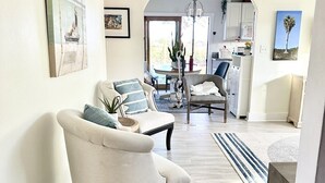Een ruime woonkamer met een grote bank, een eethoek met een tafel en stoelen, en een keuken die zichtbaar is door een boog.
