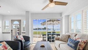 Ein Wohnzimmer mit einer Couch, Sesseln, einem Couchtisch und Blick durch eine Glastür auf eine Außenpatio.