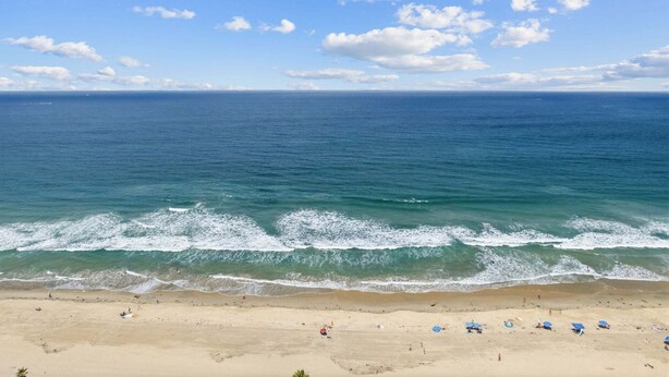 Ein Strand mit Wellen, blauem Himmel und weiter Ferne.