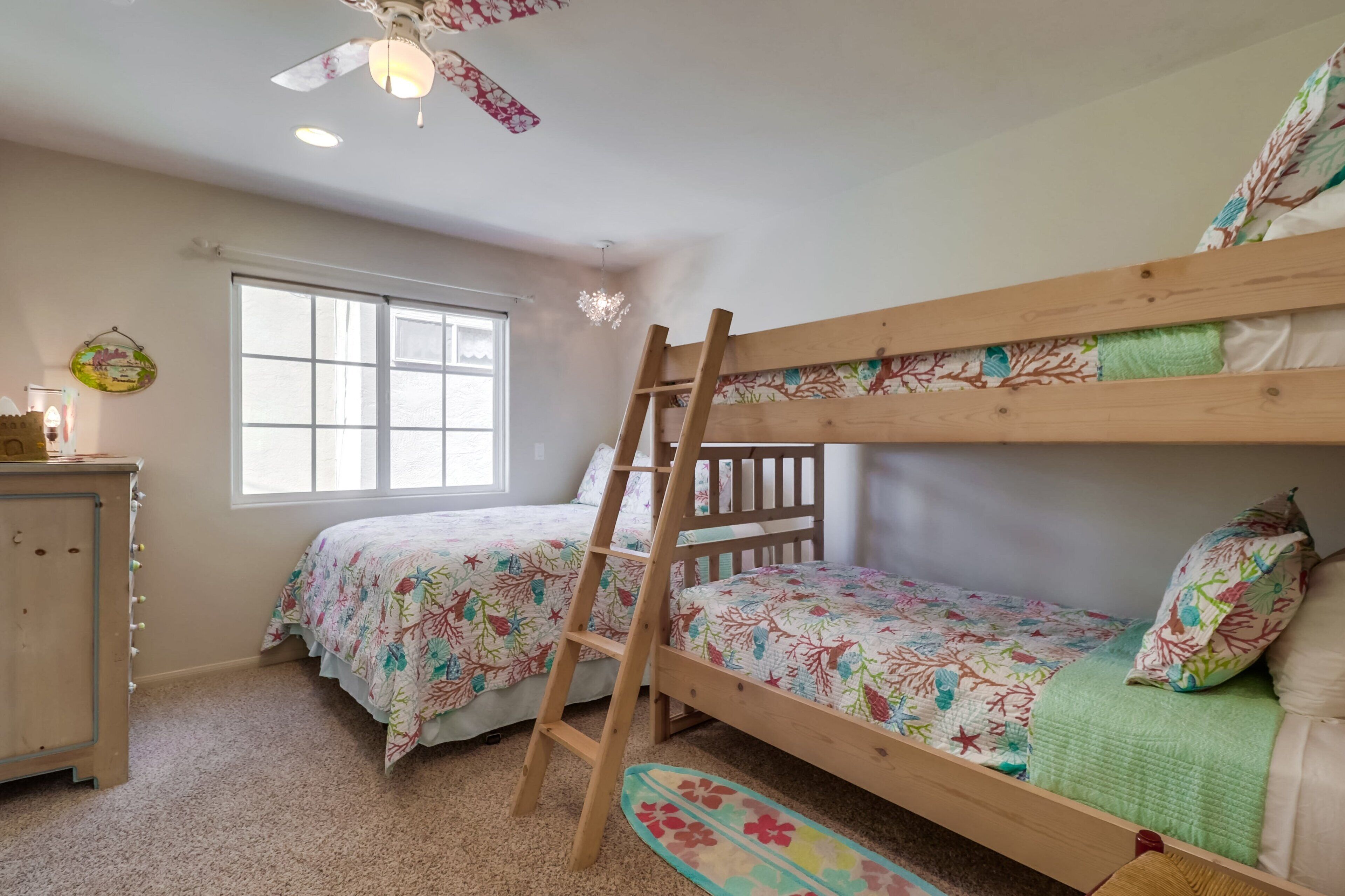 Un dormitorio con literas, una escalera, una ventana y un aparador.