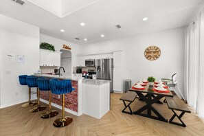 Una cocina moderna con gabinetes blancos, electrodomésticos de acero inoxidable y una pared de ladrillo decorativa.