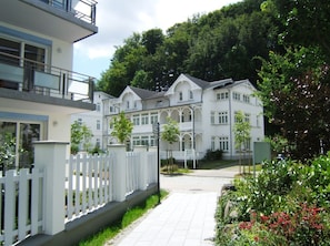 A large, white, multi-story building with a symmetrical facade, a gated entrance, and a paved pathway leading to it. - Villa Amanda - Strandnahe Fewo in Zentraler Aber Ruhiger Lage in Binz - Villa Amanda Fewo Nr.09 (Binz)