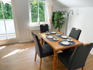 Comedor con una mesa de madera preparada para cuatro personas, rodeada de sillas negras.