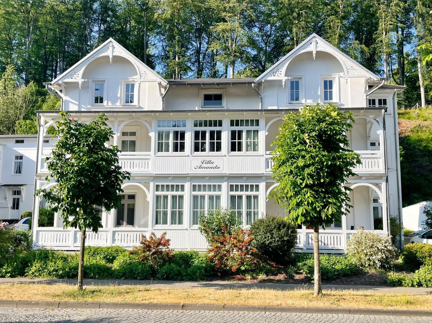 Un edificio grande y blanco de dos pisos con un balcón y un letrero que dice 'Villa Amanda'.