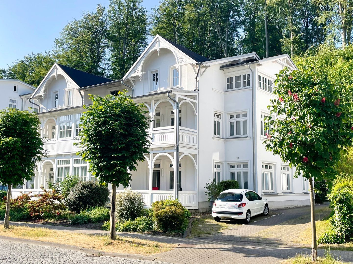 Un edificio blanco de varios pisos con un estilo arquitectónico clásico, con balcones y ventanas grandes.