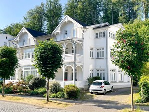 Un edificio blanco de varios pisos con un estilo arquitectónico clásico, con balcones y ventanas grandes.