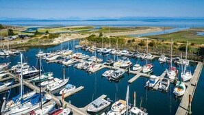 Un port de plaisance où de nombreux bateaux sont amarrés dans une baie tranquille, entourée d’étendues d’eau et de terres lointaines.