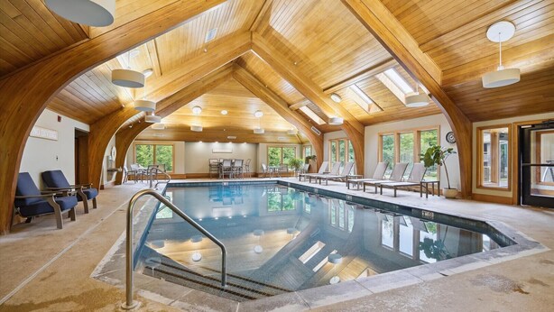 A large indoor swimming pool with wooden beams and natural light. - Welcoming Two condo with pool, hot tub, and more- J3 (Killington)