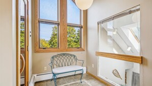 A room with a bench, a window with a view of trees, and a glass door with a geometric design. - Welcoming Two condo with pool, hot tub, and more- J3 (Killington)