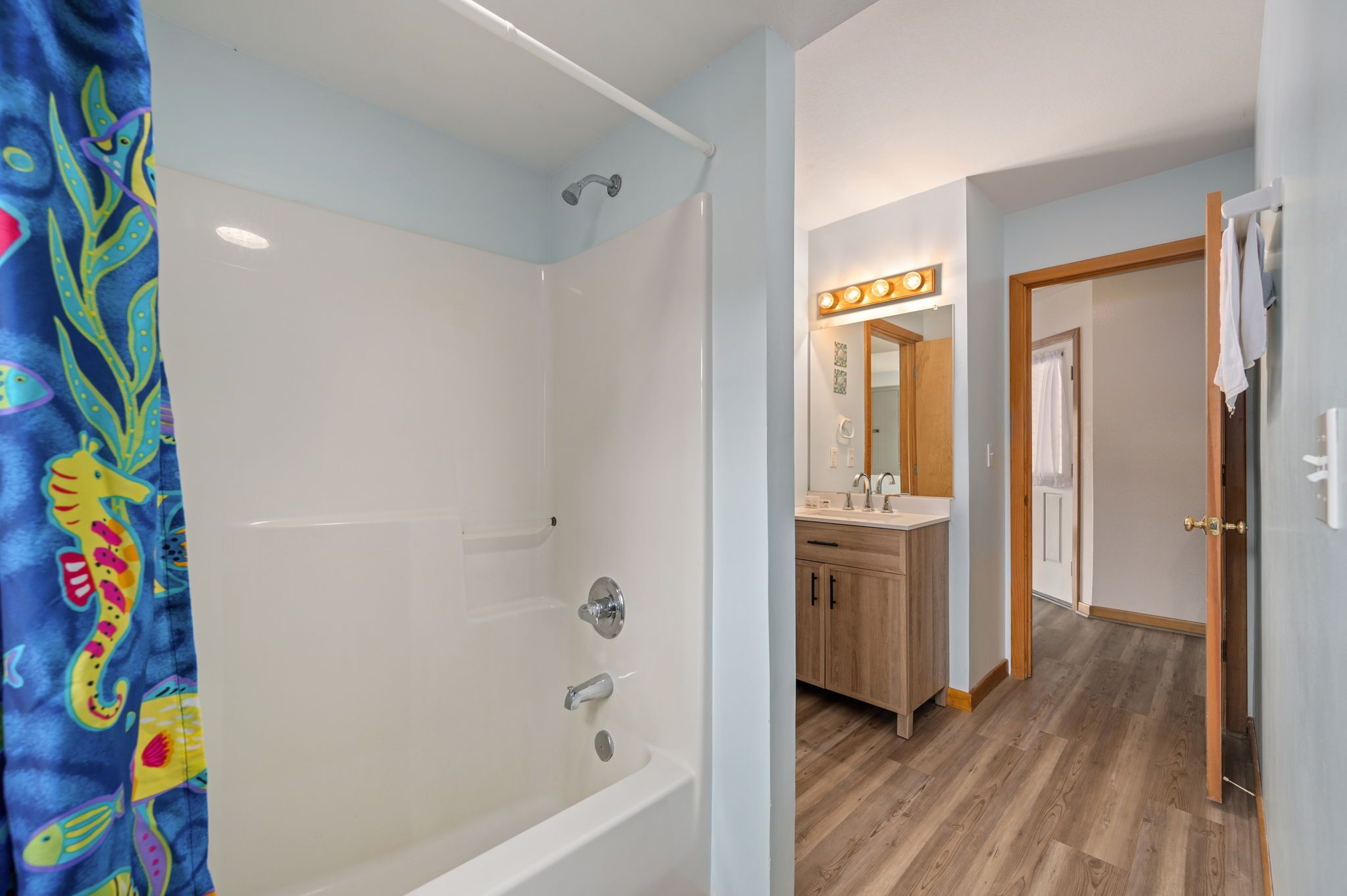 Une salle de bain équipée d’une baignoire, d’une douche et d’un meuble-lavabo avec un miroir et des luminaires.