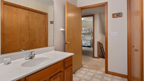 A bathroom with a wooden vanity, a large mirror, and a sink. - Sunshine Daydream - Oceanside, Private Pool, Hot Tub and Game Room (Corolla)