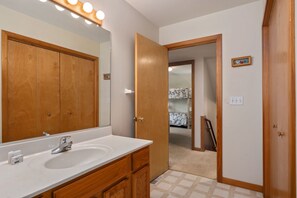 A bathroom with a wooden vanity, a large mirror, and a sink. - Sunshine Daydream - Oceanside, Private Pool, Hot Tub and Game Room (Corolla)