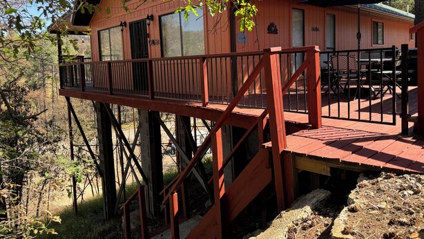 Una cabaña de madera con un porche y una escalera que lleva a un balcón en el segundo piso.