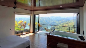 Quarto moderno com cama grande, banheira e varanda com vista para as montanhas.