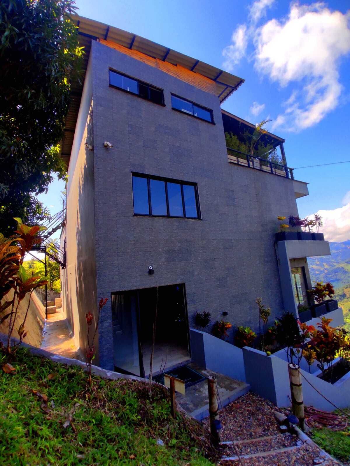 A modern two-story building with a flat roof, large windows, and a balcony.