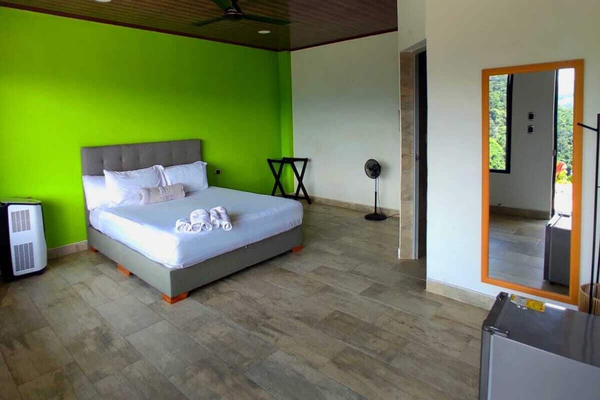 Een slaapkamer met een bed, een ventilator en een verwarming.