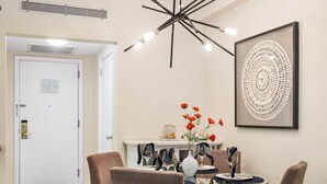 Un coin repas comprenant une table ronde, quatre chaises, un lustre moderne et une œuvre d’art encadrée accrochée au mur.