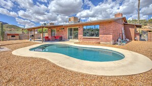Ein modernes Haus mit Swimmingpool, Terrassenmöbeln und einer überdachten Außenbereich.