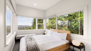 Enjoy a scenic view from the large bed with a headboard, surrounded by expansive windows.