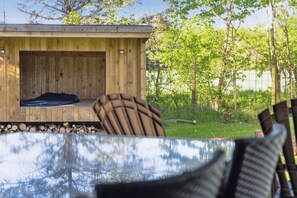 Una cabaña de madera con una plataforma elevada y un espacio cerrado, rodeada de árboles y una valla.