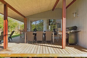 Un patio al aire libre con terraza de madera, pared de ladrillo y zona de barbacoa.