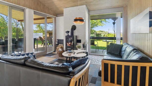 Una sala de estar moderna con chimenea, un sofá de cuero y un comedor con mesa y sillas.