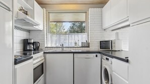 Una cocina compacta equipada con lavavajillas, horno, microondas y ventana con vistas.