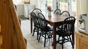 A spacious kitchen with a dining area, large windows, and a ceiling fan. - Green Acres - Lake Access - Hot tub - Fire pit (Swanton)