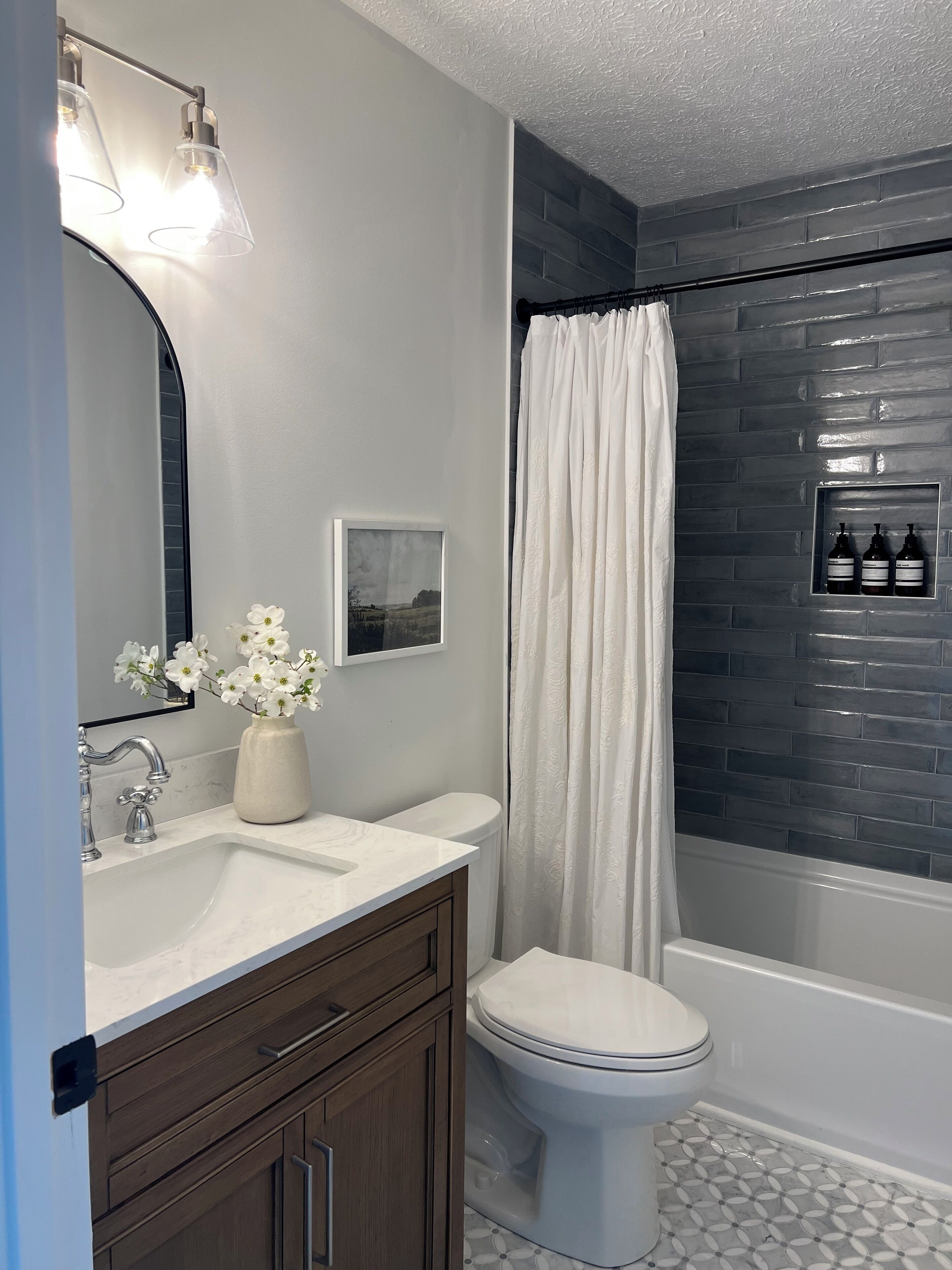 A bathroom with a white sink, a mirror, a toilet, and a shower curtain.