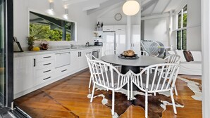 Une cuisine moderne avec des meubles blancs, une table de salle à manger ronde et des chaises blanches.
