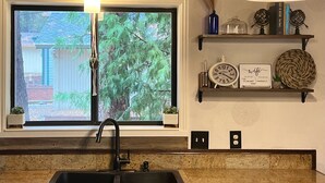 A kitchen with a window, a sink, and a shelf with decorative items. - Near Yosemite & Lake & On Golf Course (Groveland)