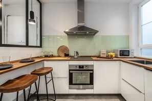 Modern kitchen with stainless steel range hood, oven, double sink, and microwave.