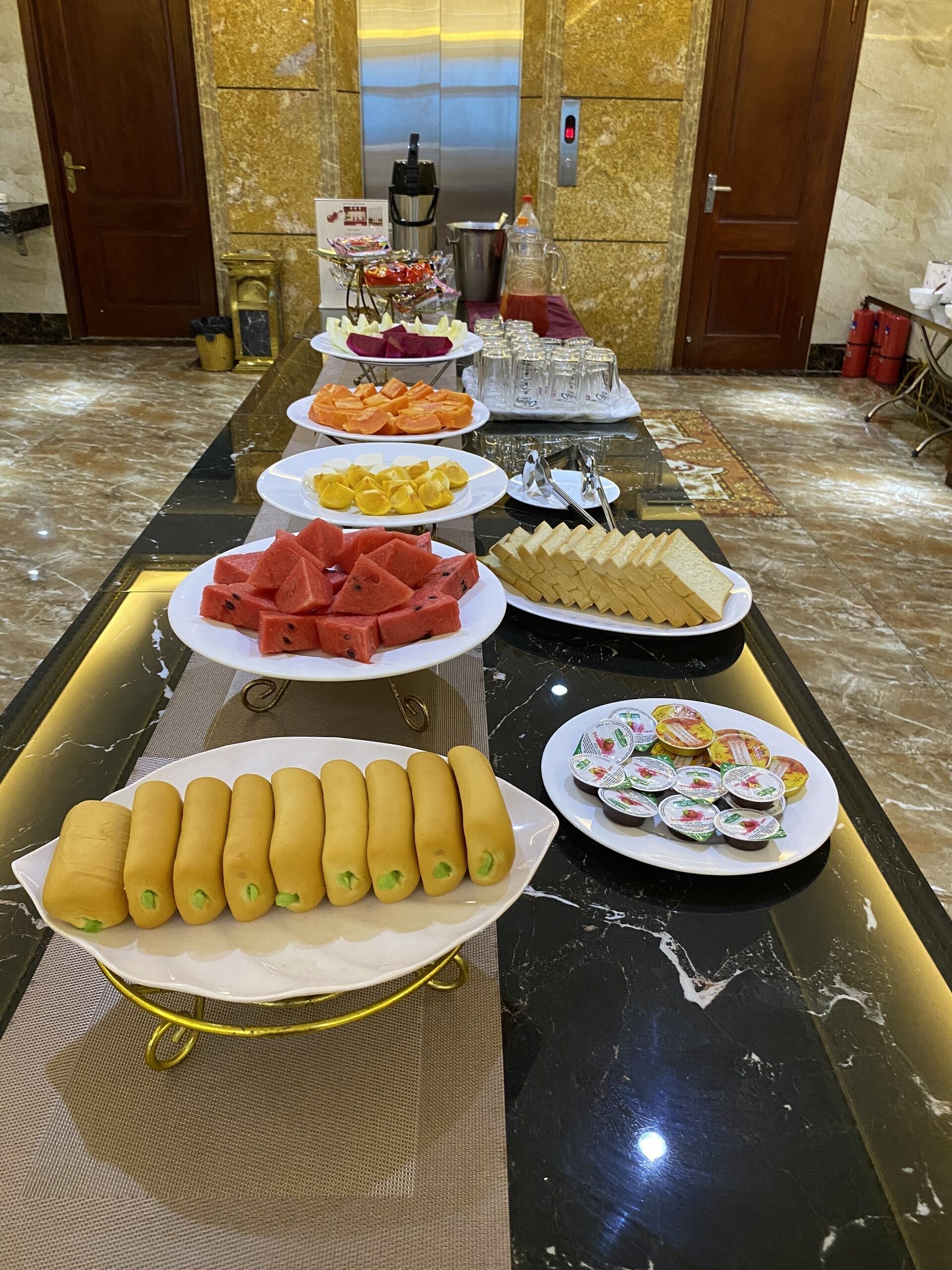 Ein Buffet mit verschiedenen Speisen, darunter Wassermelone, Brot und Joghurt.