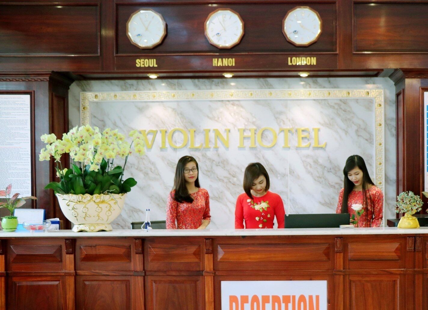 Una mesa de recepción en el Hotel Violin con relojes que muestran las horas de Seúl, Hanói y Londres.