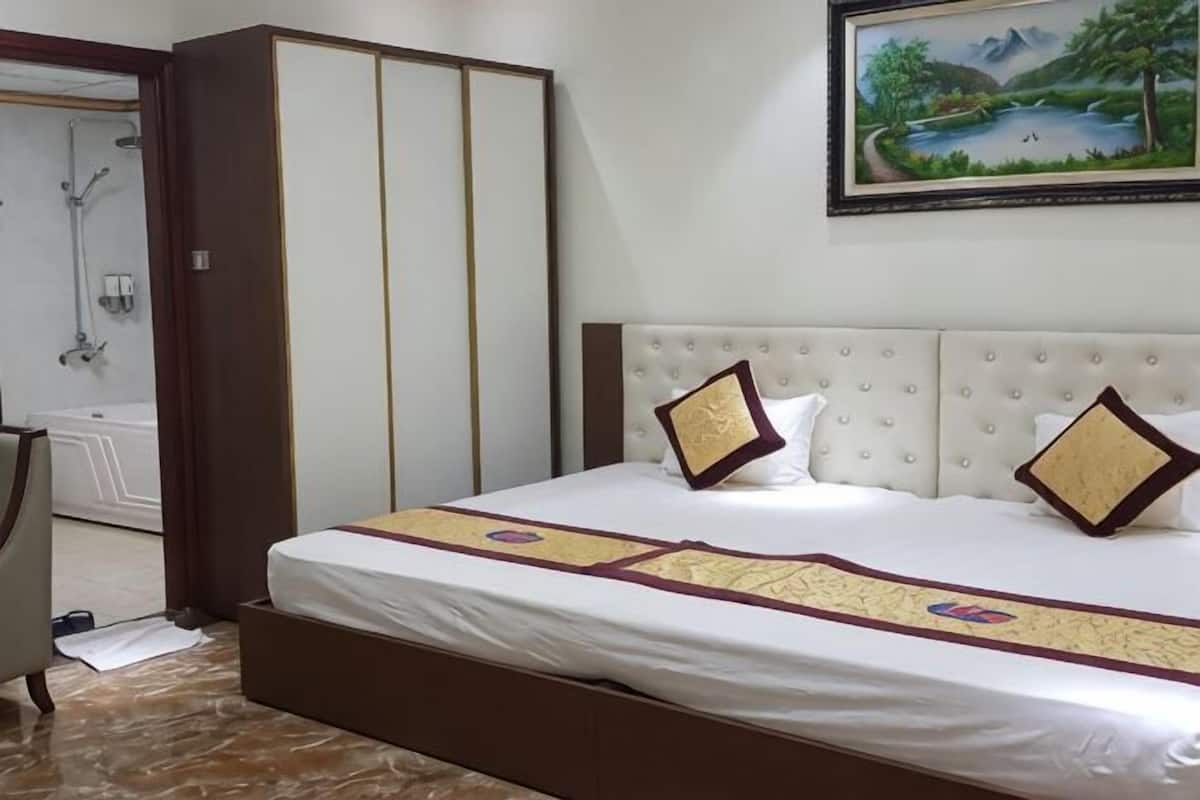 A hotel room with a bed, a wardrobe, a painting, and a bathroom.