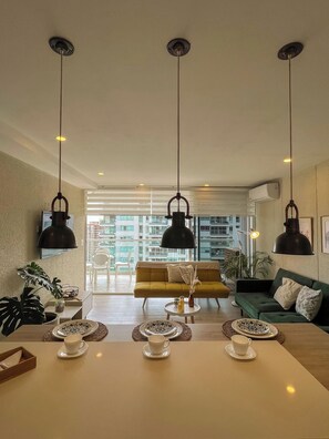 A spacious living area with a sofa, coffee table, and hanging pendant lights. - Exclusive oceanfront apartment featuring a private jacuzzi on the balcony (La Boquilla)