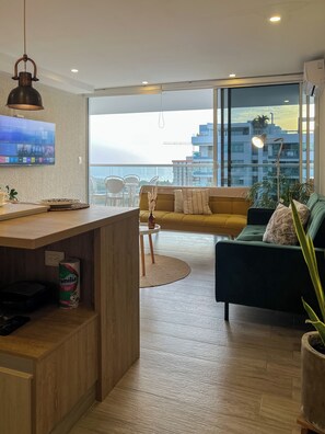 Un salon moderne avec un plancher en bois, un canapé vert, une table basse ronde et un téléviseur fixé au mur.